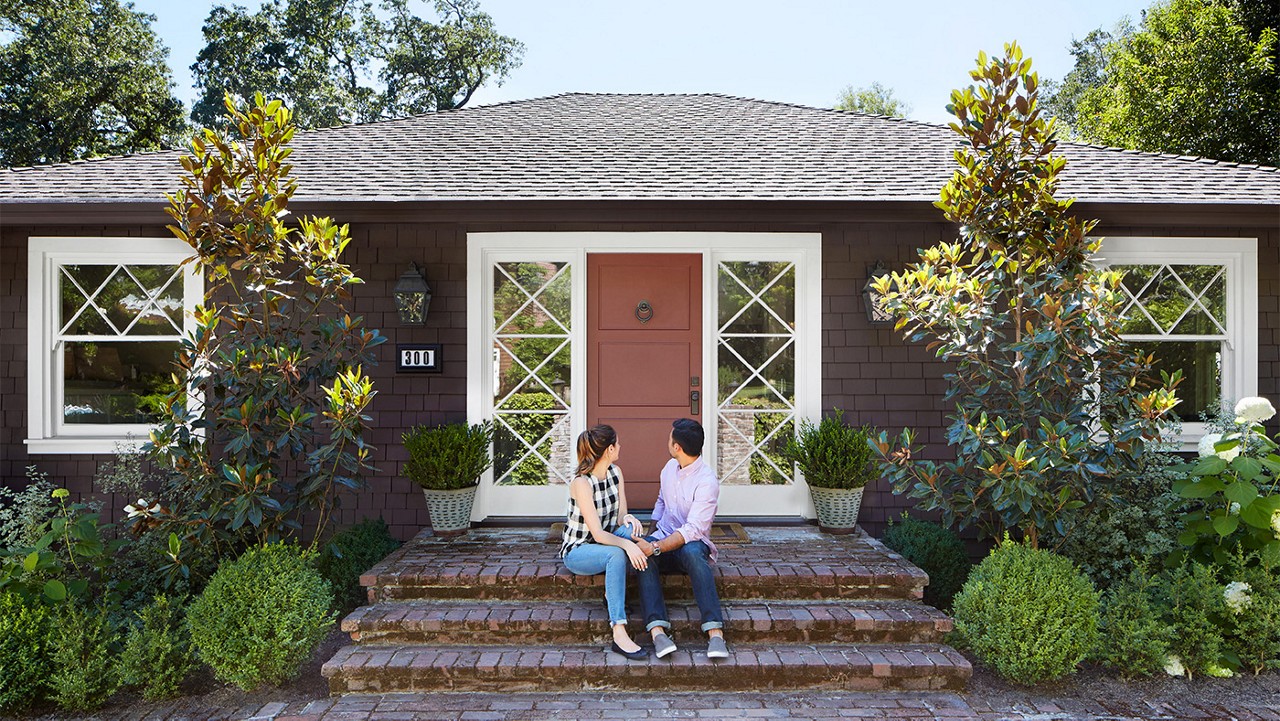 Young couple sitting on the front steps of their home  Young couple sitting on the front steps of their home