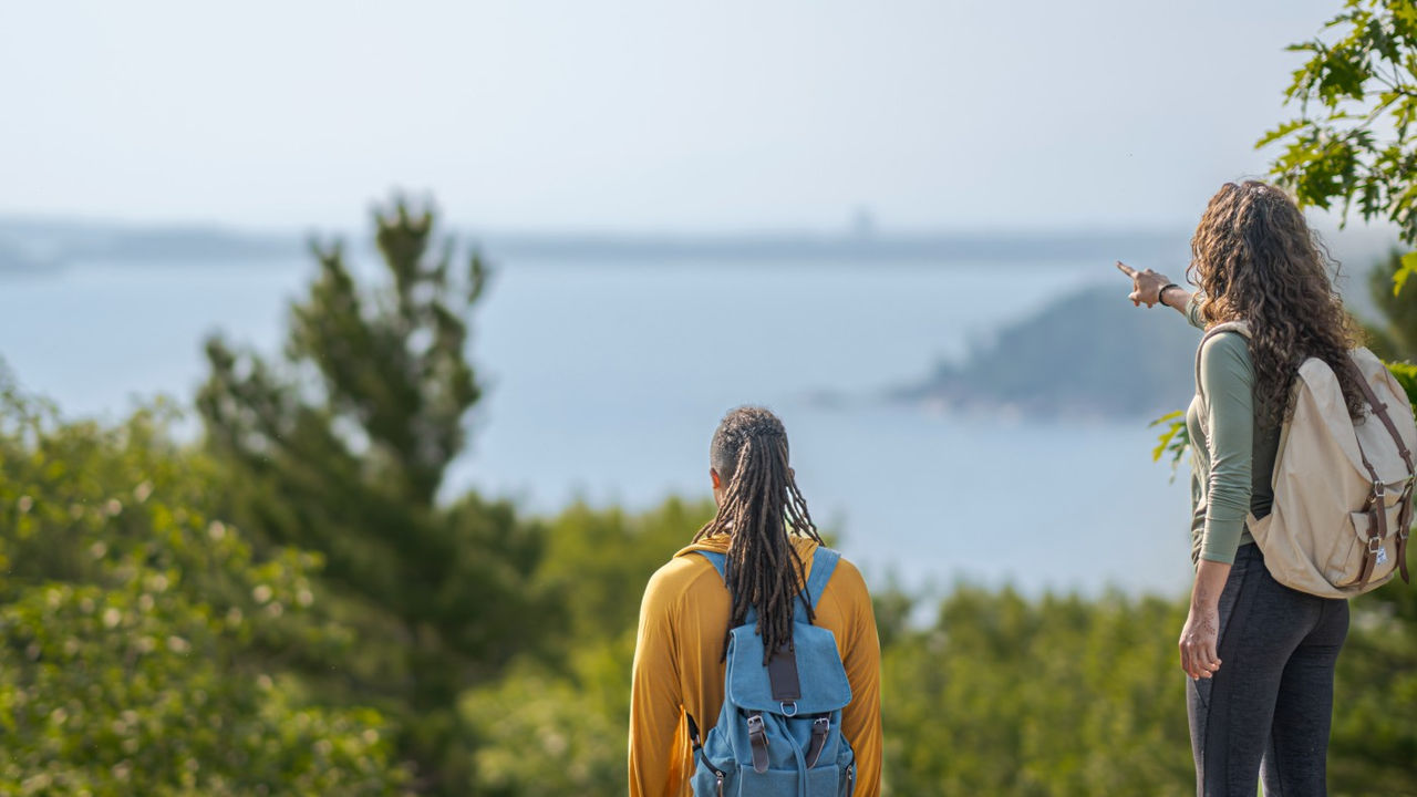 Two hikers admire a scenic view overlooking Lake Superior 